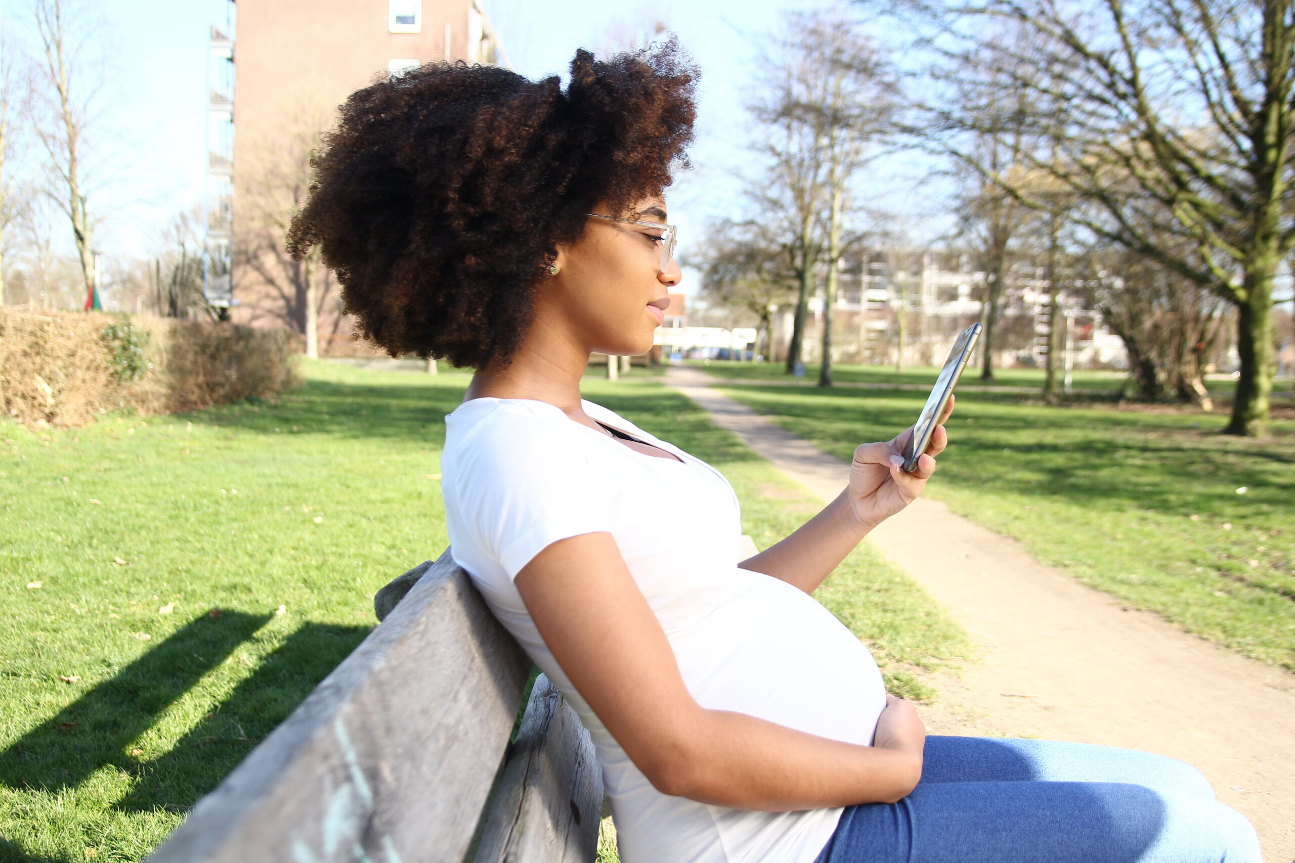 pregnant black student sits on a bench on campus